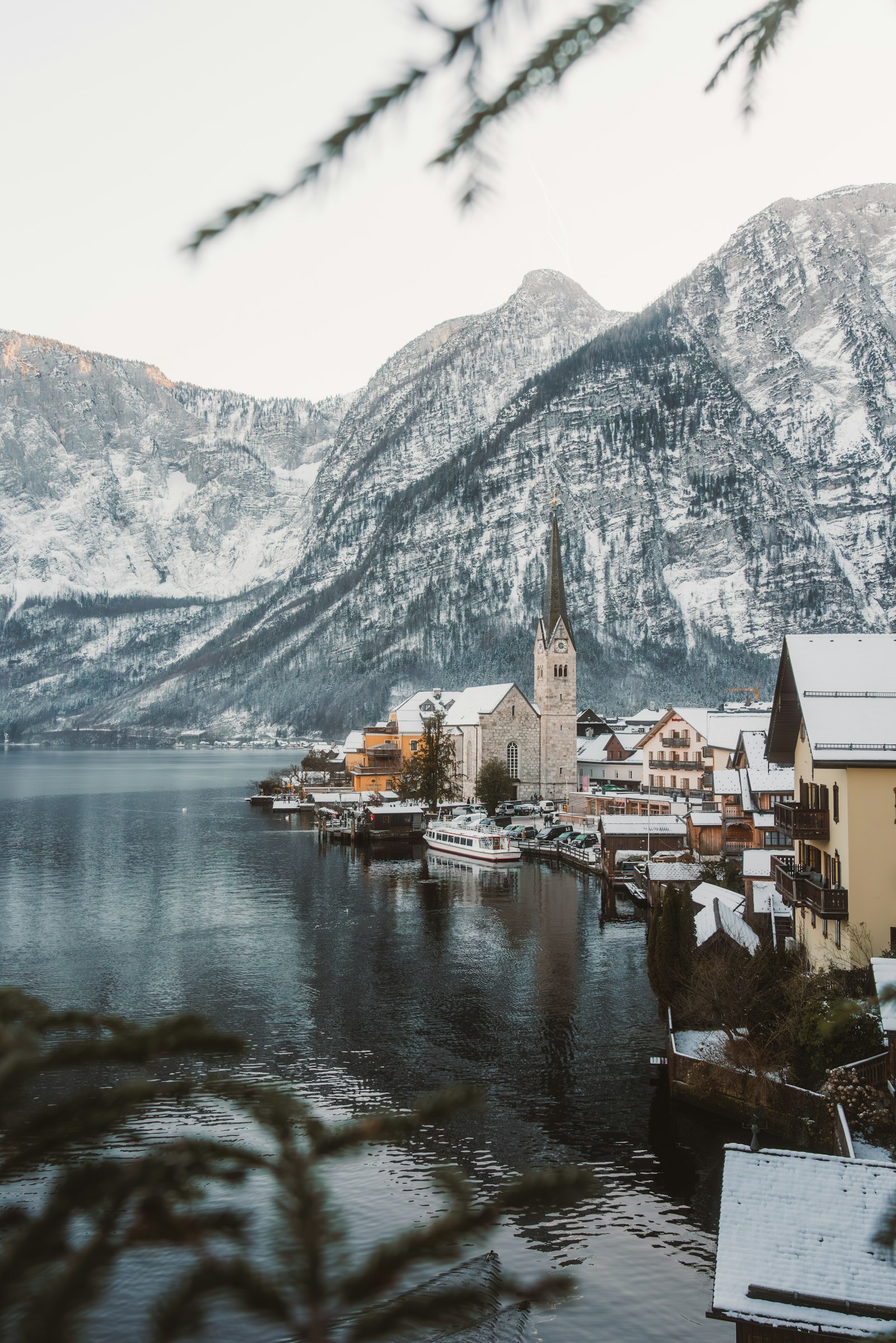 A snow-dusted lakeside village with a church spire and a docked boat